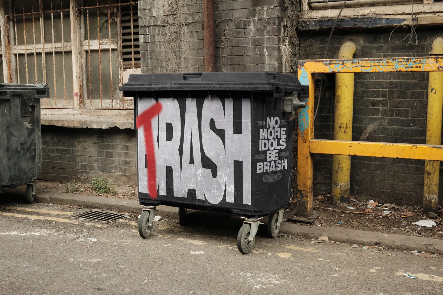 Urban dumpster with bold graffiti text "TRASH" for graphic design mockup, showcasing street art typography and urban decay setting.